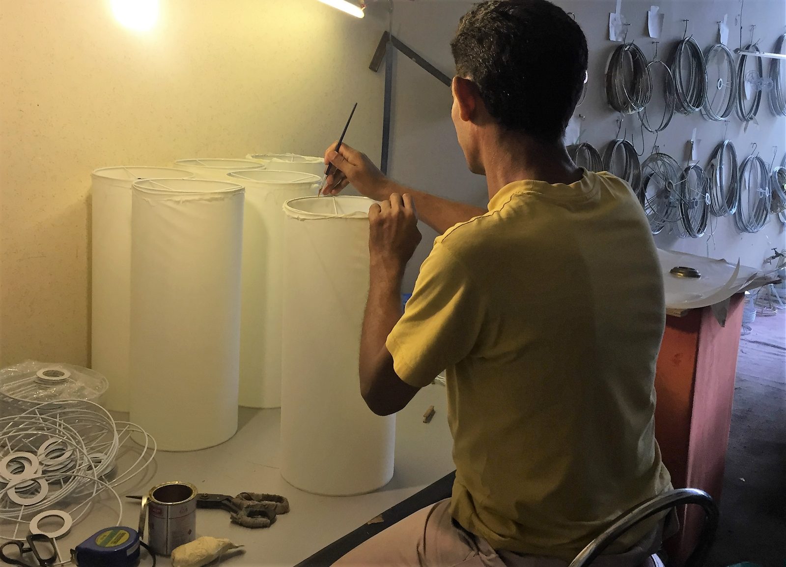 A Citizone craftsman hand-stitching the fabric of a lampshade